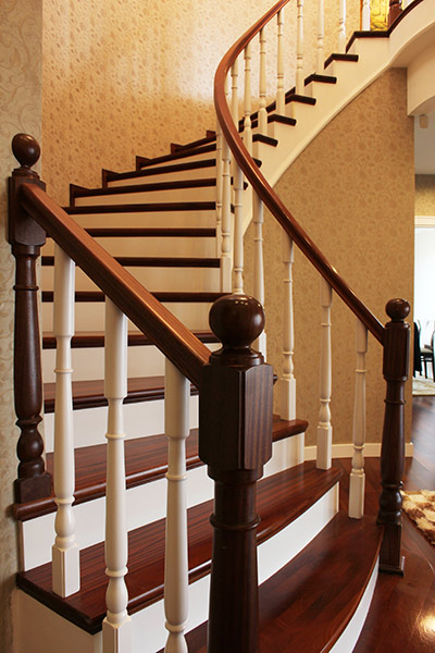 Elegante geschwungene Holztreppe mit dunklem Gelaender und weissen Balustern