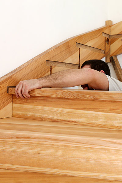 Ein Mann montiert konzentriert eine Holztreppe aus hellem Naturholz