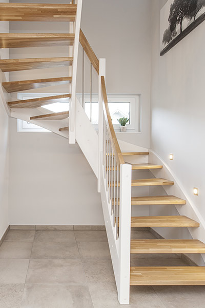 Eine helle Holztreppe mit weissem Gelaender und Stufen aus hellem Holz