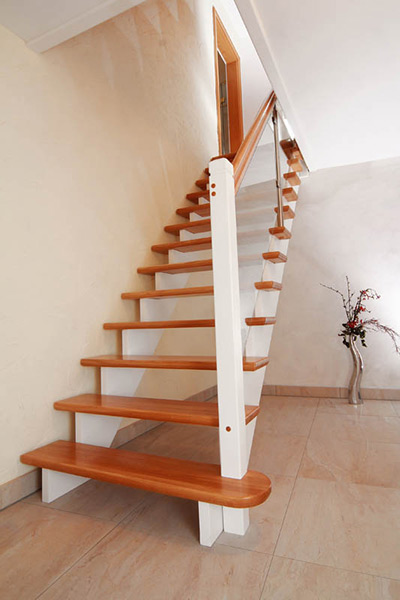 Moderne Treppe mit Holzstufen und Glasgelaender neben einer Vase mit Zweigen